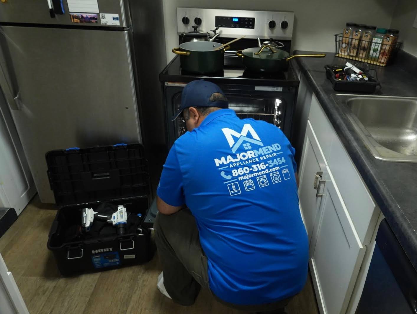 MajorMend technician working on an oven in a home kitchen